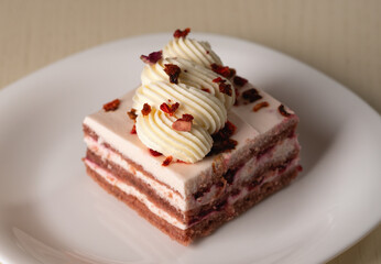 A slice of layered cake with a soft texture, cream rosettes, and dried berries