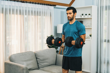 Athletic body and active sporty man lifting dumbbell weight for effective targeting muscle gain at gaiety home as concept of healthy fit body home workout lifestyle.
