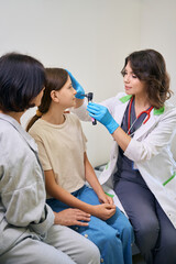 Young doctor uses a special instrument to examine