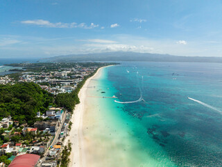 Tropical white sand beach with waves and boats over clear waters. Boracay Island. Philippines.