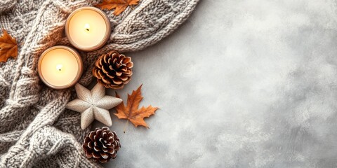 Autumn-inspired cozy setting with knit fabric, lit candles, pinecones, and dry leaves against a neutral background, perfect for relaxing and unwinding.