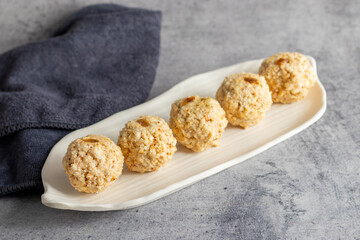 Moa is a traditional Bengali sweet made of puffed rice, jaggery, and coconut, often shaped into small, round balls.