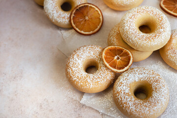 Donuts with orange flavor and powdered sugar on baking paper high angle view