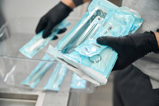 Medical technician putting sterile tools in heat-sealing packages into transparent container