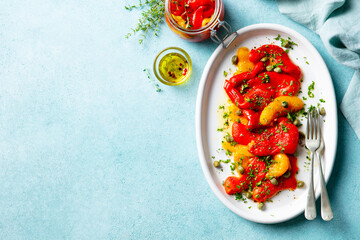 Grilled yellow and red bell pepper salad with capers and olive oil. Blue background. Copy space. Top view.