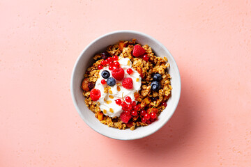 Healthy breakfast. Granola, muesli with yogurt and fresh berries. Pink background. Top view.