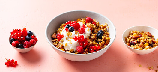 Healthy breakfast. Granola, muesli with yogurt and fresh berries. Pink background. Close up.