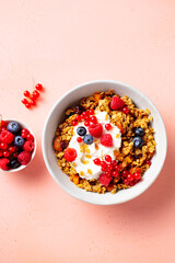 Healthy breakfast. Granola, muesli with yogurt and fresh berries. Pink background. Copy space. Top view.
