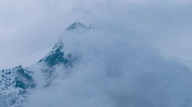 4K Time lapse of dark clouds moving around snow covered mountain peak in Manali, India. Nature background of early winter.