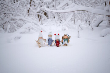 Toy angels in knitted hats and scarves. Christmas decorations. Snow background.