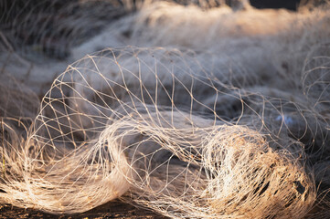 Fishermen's tools on shore display intricate fishing nets at sunrise