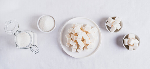 Alternative choice between lump sugar and granulated sugar on white top view web banner