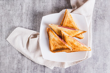 Close up of grilled triangle sandwiches with cheese and sausage on a plate on a table top view