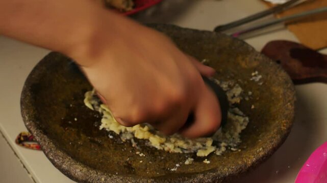 4k video of pounding garlic and pepper for cooking spices. Close up video of finely mashing onions as a cooking spice.