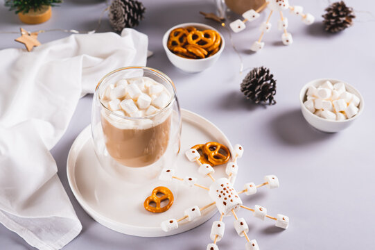 Hot chocolate with marshmallows and pretzels and snowflake made of candies on a plate