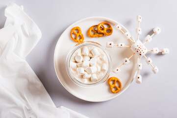 Close up of cocoa in cups and snowflakes made of marshmallows and icing on a plate top view