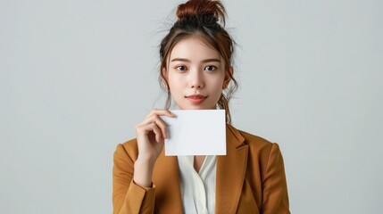  A woman dressed in a business outfit, holding a blank ad card in front of her, against a seamless white backdrop