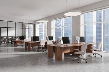 Modern open office space with wooden desks, ergonomic chairs, and large windows overlooking city skyline, with gray concrete floor. 3D Rendering