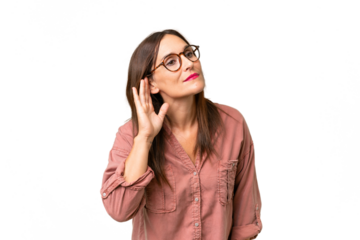 Middle-aged caucasian woman over isolated background listening to something by putting hand on the ear
