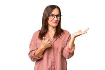 Middle-aged caucasian woman over isolated background holding copyspace imaginary on the palm to insert an ad and with thumbs up