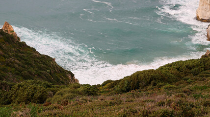 a vertical shot of a cliff with a cliff and a beautiful green grass