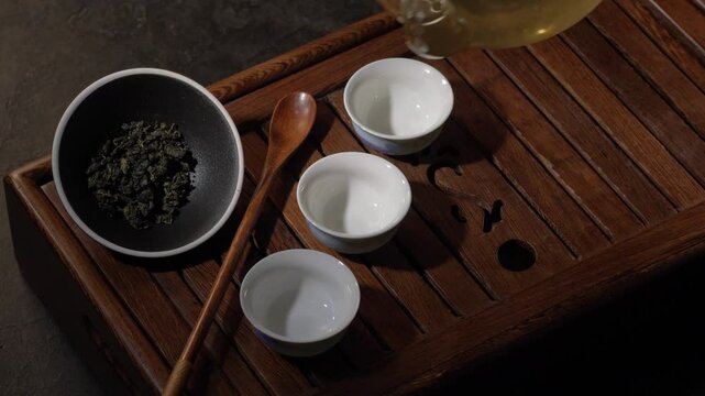 Tea ceremony on dark background. Pouring green tea in cup. 