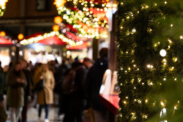 Naklejka premium Besucher auf einem Weihnachtsmarkt am Abend