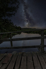 Old wooden bridge and the Milky Way in the night sky © Karol