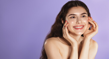 Close up portrait of young woman smiling, touching clean hydrated face after skincare treatment,...