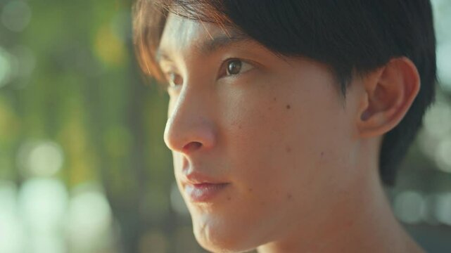 Closeup of face asian male opening eyes looking straight while thinking of goal for exercise before running in public park