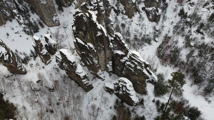 A breathtaking winter aerial panorama of Prachovske Skaly near Jicin, featuring snow-covered sandstone formations and the beauty of Czech nature during the colder months.