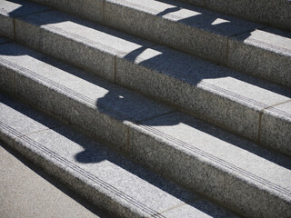 Detail of stairs made of gray concrete in sunny weather with a human shadows 