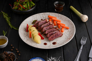 Grilled beef steaks and vegetables, With cooked carrots and mashed potatoes, black wood background
