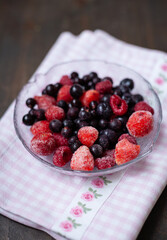 Frozen mixed fruits in a bowl - berries - strawberries, raspberries, black currants. A bowl with berries on a beautiful fabric