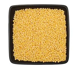 Peeled yellow millet seeds in black porcelain bowl, organic food product isolated on white, top view