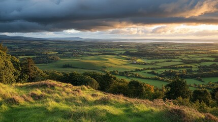 A picturesque landscape at sunset, showcasing rolling hills and lush green fields under dramatic clouds.