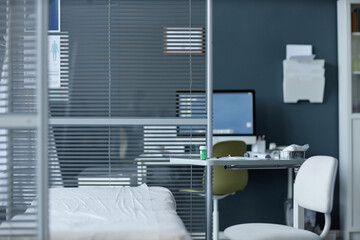Background image of medical clinic interior with hospital bed, desk and computer behind glass wall, copy space