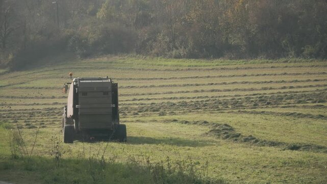 A tractor with hay baler or hay maker trailer in the field