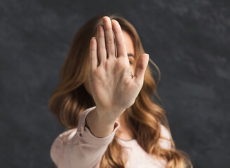 Woman showing no with her hand. Stop sign of discrimination or anti violence symbol, black studio...