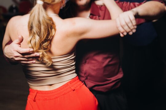 Couples dancing traditional latin argentinian dance milonga in the ballroom, tango salsa bachata kizomba lesson in red and purple lights, evening dance school class festival, performance rehearsal