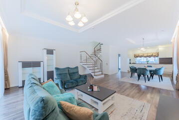 Modern Scadinavian Home Living Room. Luxurious Stylish Modern Apartment. Open Interior, Wide TV Screen Table Chairs. Couch Sofa, Coffee Table Scandinavian Design. Windows and Curtains Kitchen Upstairs