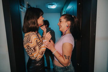Two friends share a joyful moment during a lively party, exchanging laughter and happiness in a...