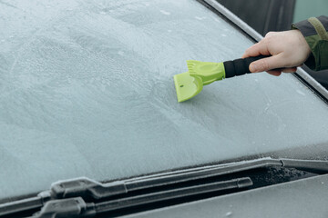 a man clears ice from the windows of his car. The night cold froze the windows. daily morning...