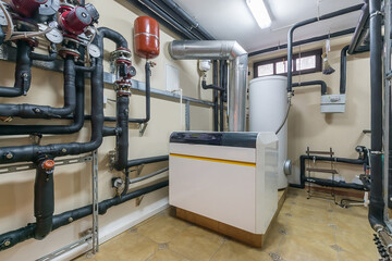 A modern boiler sits against a wall in a well-organized residential basement. Surrounding it is an...