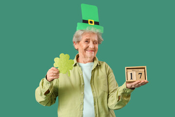 Happy senior woman in leprechaun hat with paper clover and calendar for St. Patrick's Day...