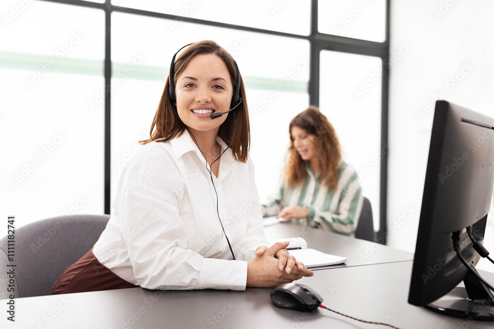 Poster two women are engaged in work in a contemporary office. one is wearing a headset and smiling while u