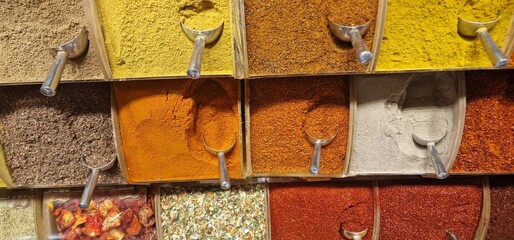 Many different colored spices with small spice scoops