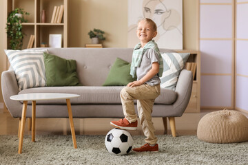 Happy boy with soccer ball playing in room