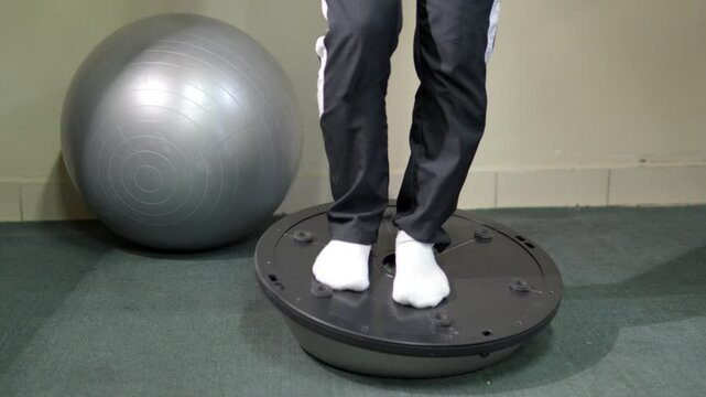 A young male athlete doing physiotherapy rehabilitation exercise on a bosu, stability exercise.