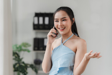 Smiling Businesswoman on Phone Call: A young woman in a blue top radiates warmth and professionalism as she engages in a phone conversation, her smile suggesting a positive and productive interaction.